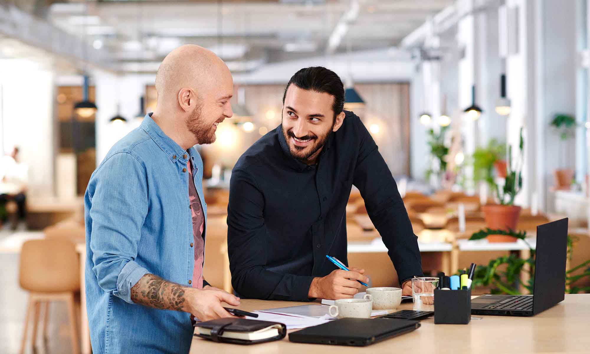 Two men at a workplace smiling at each other