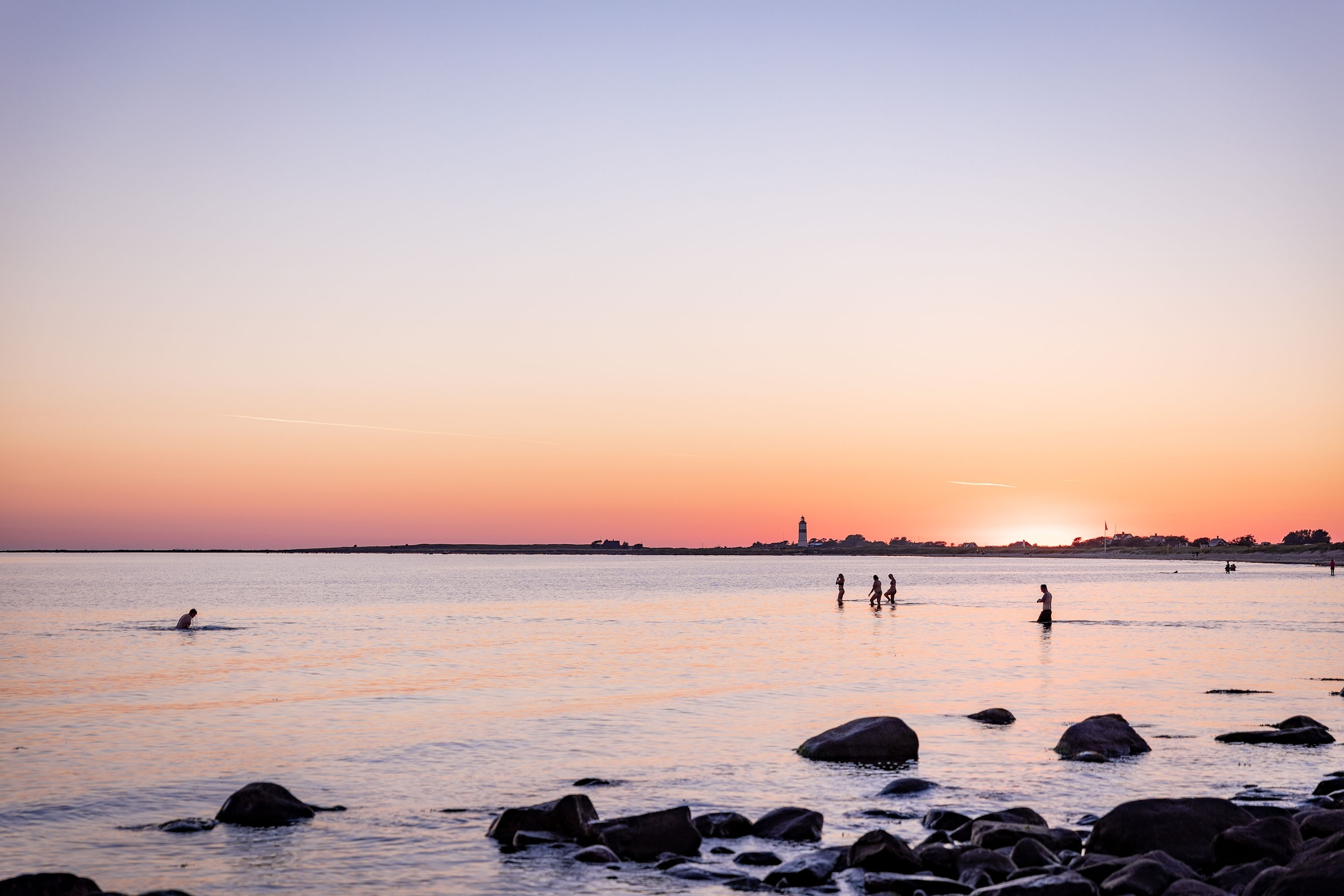 Solnedgång över en strand med badande människor