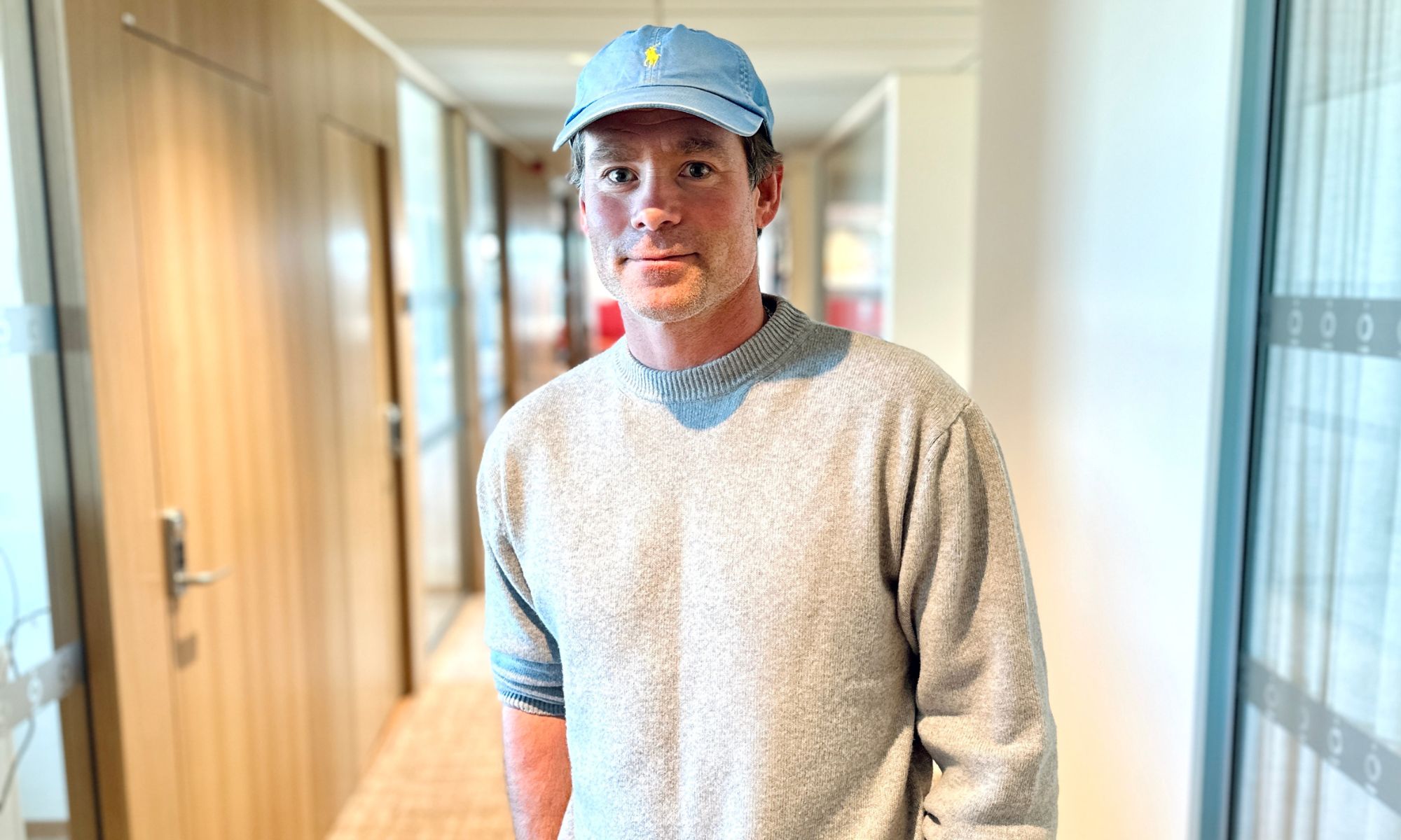 En man med keps står i en korridor